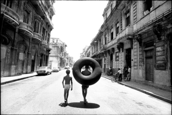 A man and woman walking down the street with an inflatable donut.
