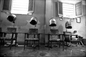 A row of chairs with hair dryers on them.