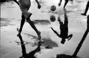 A group of people playing soccer on the beach.