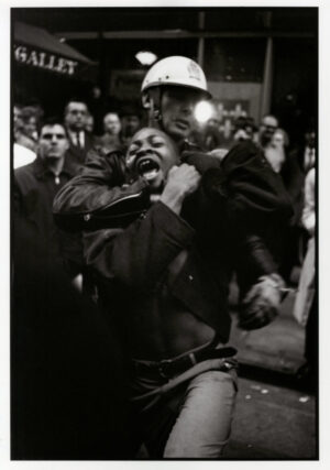 A man in a helmet is being held up by another man.