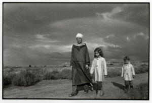 A man and two children are standing in the grass.