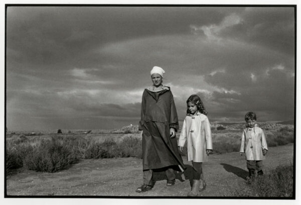 A man and two children are standing in the grass.
