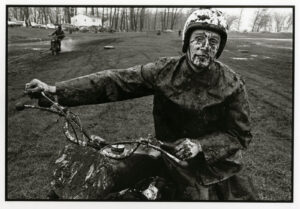 A man riding on the back of a motorcycle covered in mud.