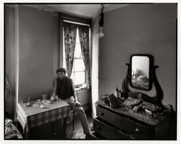 A man sitting at the table in front of a mirror.
