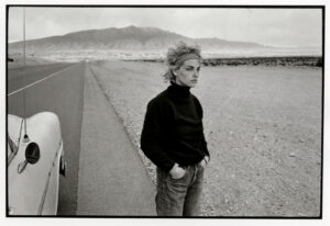 A woman standing on the side of a road.