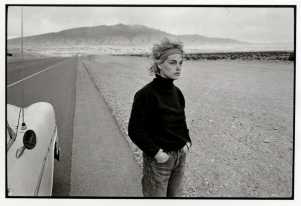 A woman standing on the side of a road.