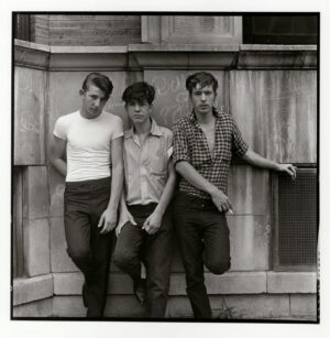 Three young men pose for a picture in front of a building.