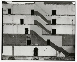 A black and white photo of some stairs on the side of a building.