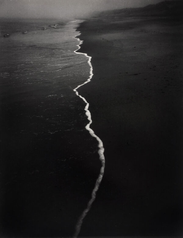 A black and white photo of the ocean shore.
