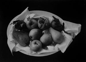 A bowl of fruit is shown in black and white.