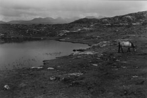A man standing on top of a hill near water.