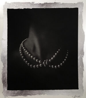 A woman wearing pearls in the dark.