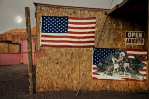 A wooden wall with two american flags hanging on it.