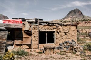 A small adobe house with a sign hanging from the side.