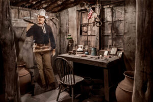 A man in an old time outfit standing next to a table.