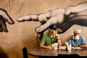 A man sitting at the table with his hand on the wall.