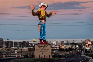 A large cowboy statue is shown in front of the city.