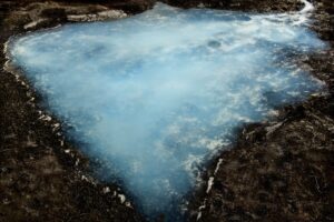 A blue pool of water in the middle of a field.