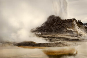 A large geyser erupting in the middle of a field.