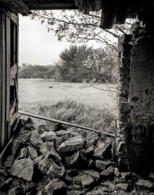 A view of a field from inside an old building.