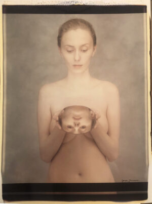 A woman holding her breast with an animal in it's hands.