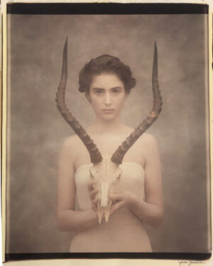 A woman holding two horns in front of her face.