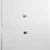 A white wall with two square metal plates.