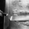 A person is holding a knife over some food.