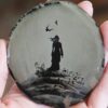 A person holding onto a small painting of a woman