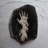 A hand with white hands is on top of a black rock.