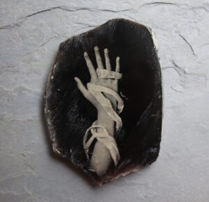 A hand with white hands is on top of a black rock.