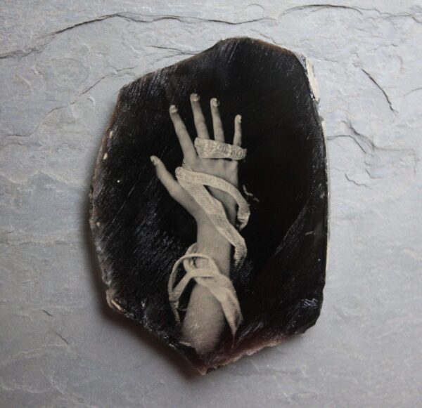 A hand with white hands is on top of a black rock.