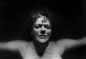 A woman with her arms spread out in the dark.