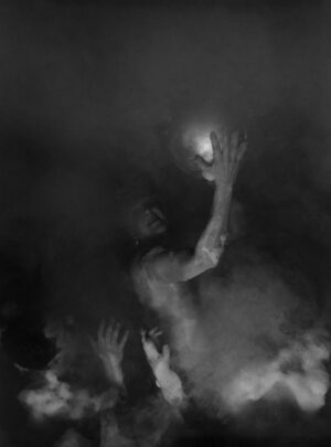 A group of people in the dark with their hands up.