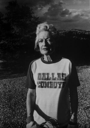 A woman standing in the grass wearing a t-shirt.