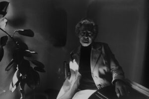 A man sitting in front of a plant.