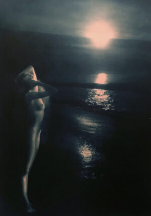 A woman standing on the beach in front of water.