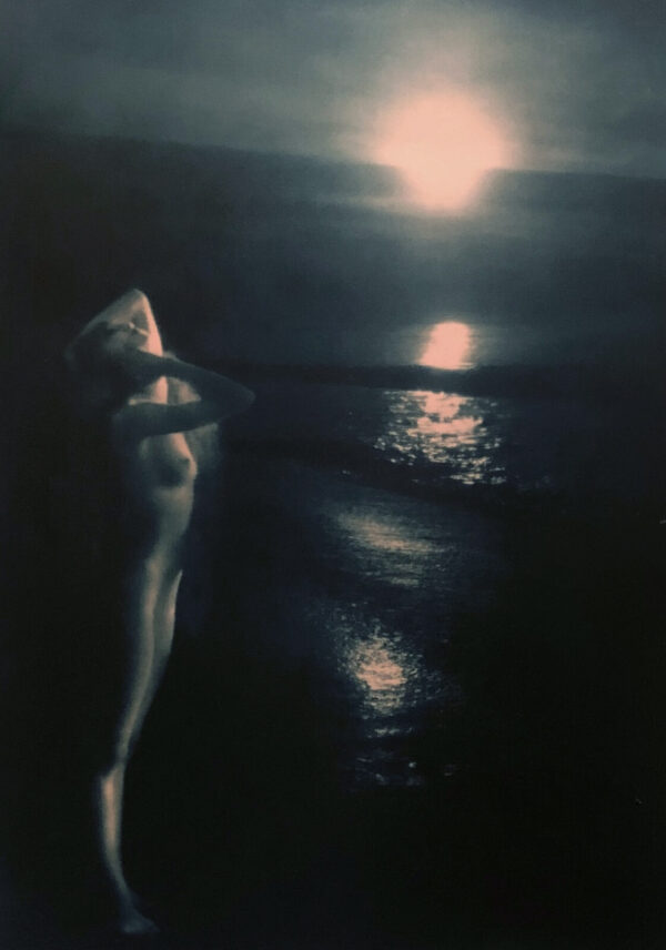 A woman standing on the beach in front of water.