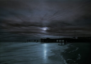 A dark sky with some clouds and water