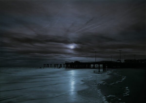 A dark sky with some clouds and water