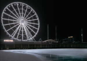 A ferris wheel on the beach at night.
