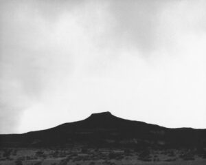 A black and white photo of a mountain with clouds in the background.