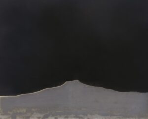 A black and white photo of a mountain with dark sky in the background.