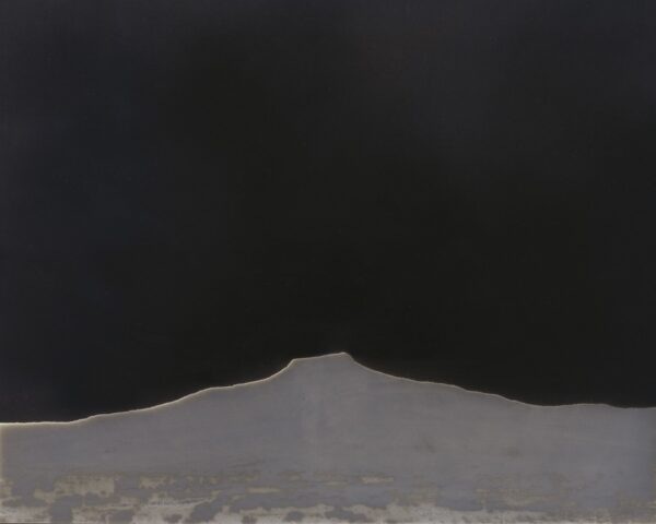 A black and white photo of a mountain with dark sky in the background.