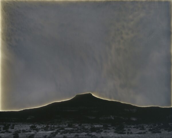 A large cloud is seen behind the mountain.