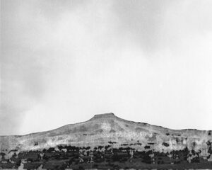 A black and white photo of a mountain with smoke coming from it.