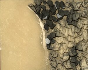 A group of rocks on the beach with water in background.