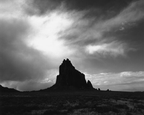 A black and white photo of some mountains under clouds
