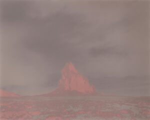 A red mountain in the distance with dark clouds.