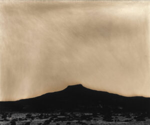 A black and white photo of a mountain with a sky background